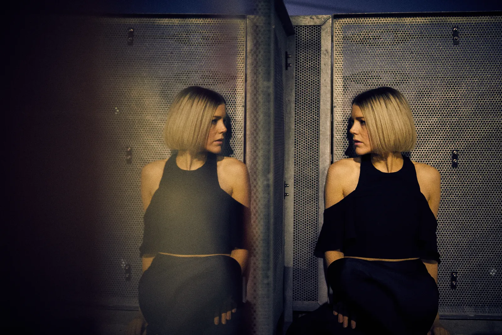 Woman leaning on wall looking beside mirror